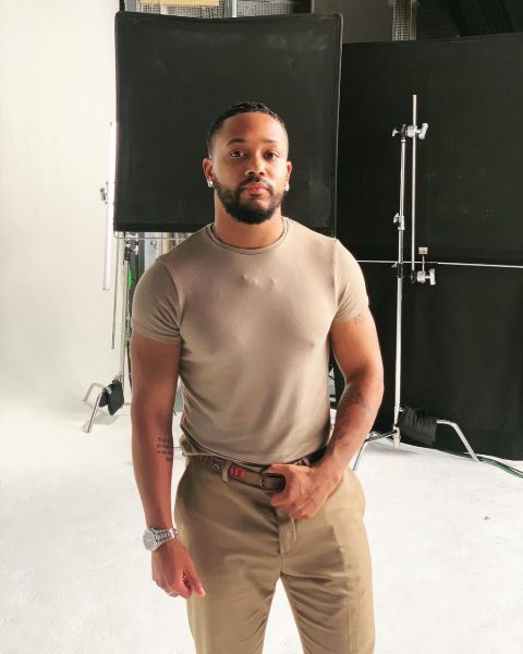 Romeo Miller poses a picture in a brown t-shirt.